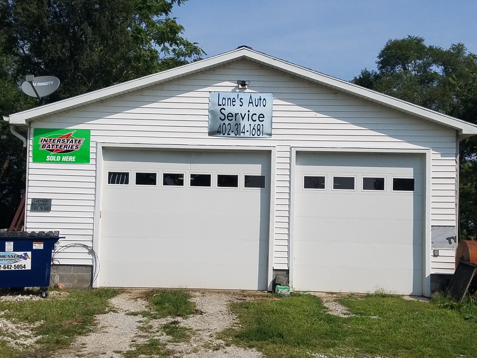 Lane's Auto Service: a white two-bay garage with an Interstate Batteries sign, on a gravel drive off County Road G.